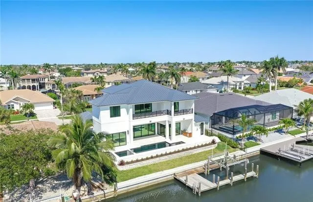 A finished waterfront residence with a metal roof, pool and dock, seen from the air