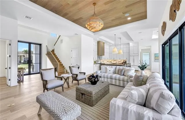 An open living room with a wood ceiling, stair, and sliders out to the yard
