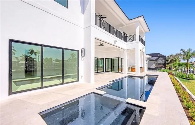 A covered lanai and pool at the back of a finished home