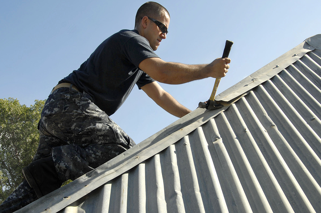 A roofer fastening a standing seam metal roof panel